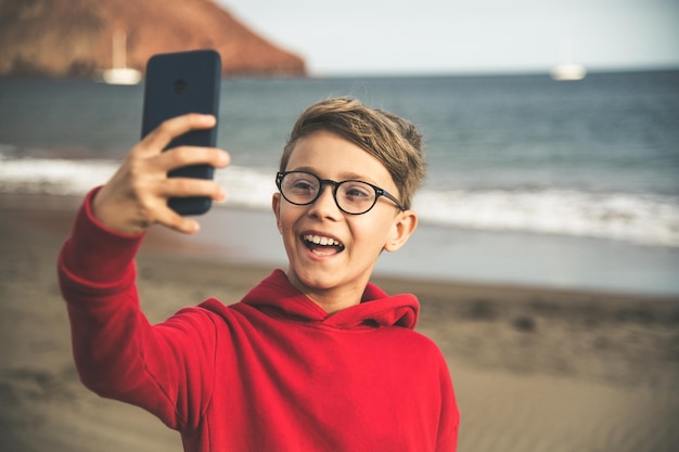 Boy taking selfie at beach against sky