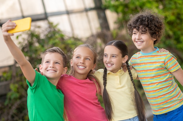 Photo boy taking selfie with friends on smartphone