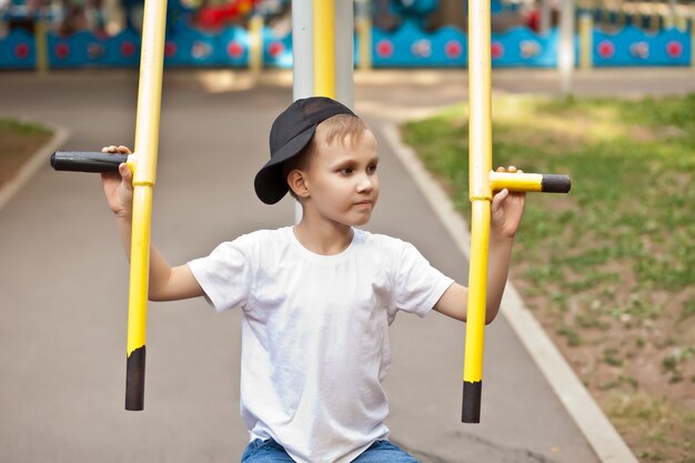 屋外の公園の遊び場でスポーツトレーニング器具を持った少年10代の子供。