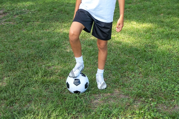 Boy teen puts his leg on ball on soccer field