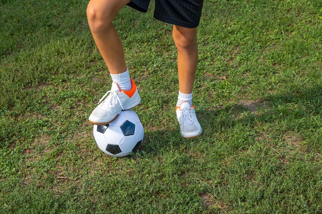 Boy teen puts his leg on ball on soccer field