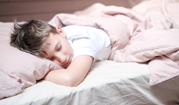 Boy teen sleeping on the bed in morning Beds blanket is in light pink colors