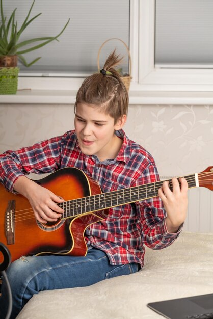 Boy teenager playing guitar at home