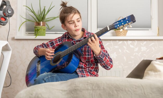 家でギターを弾く 10 代の少年