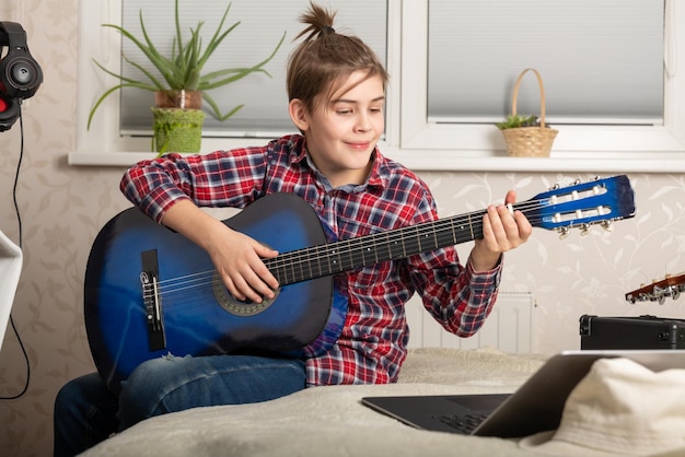 Boy teenager playing guitar at home