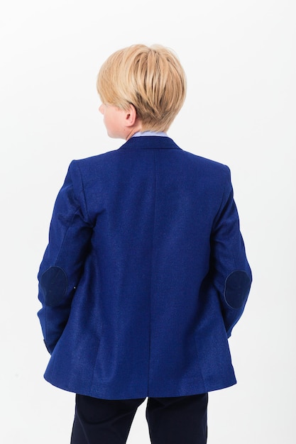 Boy teenager in a school uniform on a white background The schoolboy demonstrates black trousers and a blue jacket from behind from the back Vertical photo