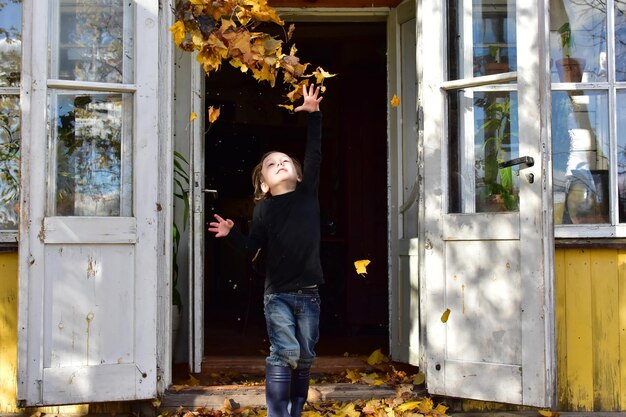 写真 ドアに乾いた葉を投げる少年