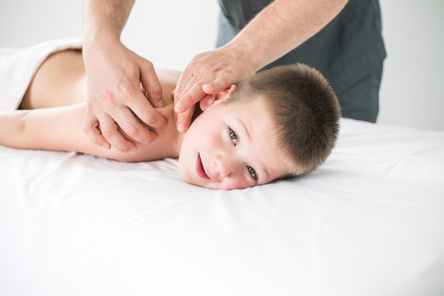 Il bambino si rilassa da un massaggio terapeutico fisioterapista che lavora con il paziente in clinica per curare la schiena di un bambino