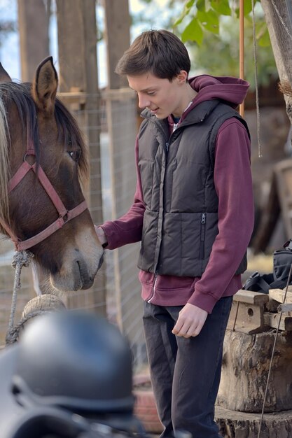 Foto ragazzo che tocca il cavallo in fattoria