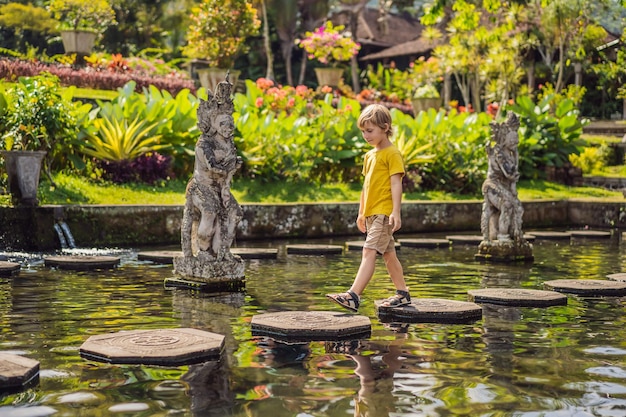 Boy tourist in Taman Tirtagangga Water palace Water park Bali Indonesia Traveling with children concept Kids friendly place