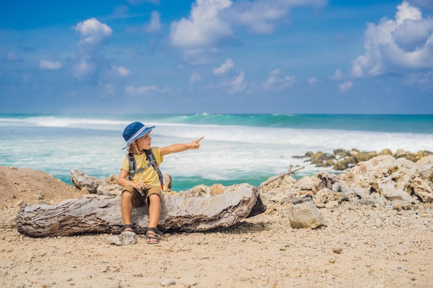 Boy traveler on amazing Melasti Beach with turquoise water, Bali Island Indonesia. Traveling with kids concept