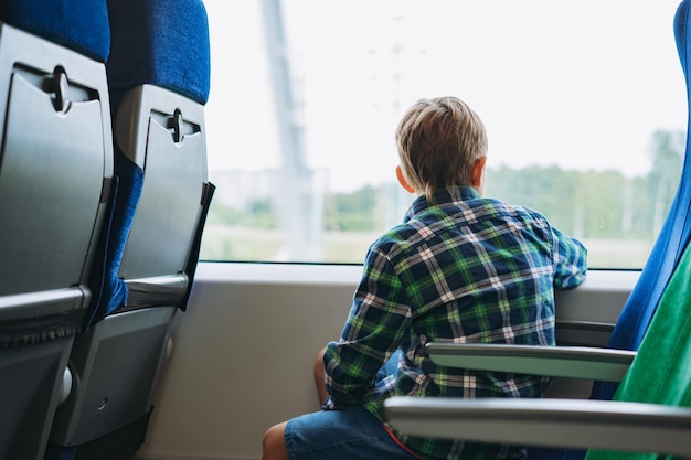 Boy travelling by train sitting by the window looking outside