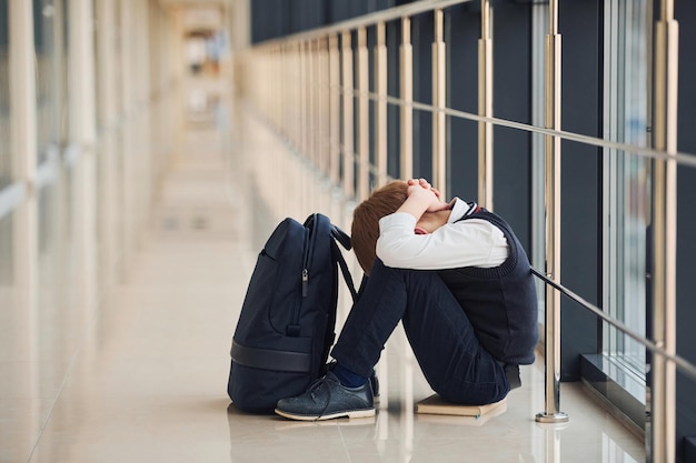 boy in uniform sitting alone with feeling sad at school conception of harassment