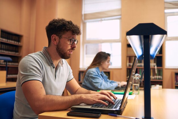 Boy uses a laptop while studying at the library