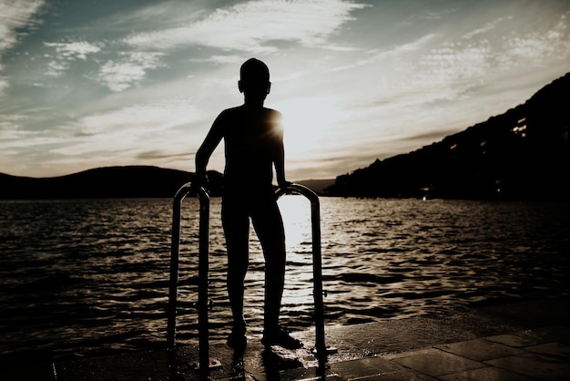 The boy uses the stairs to get out of the sea