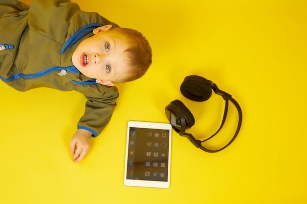 The boy uses a tablet and headphones to play