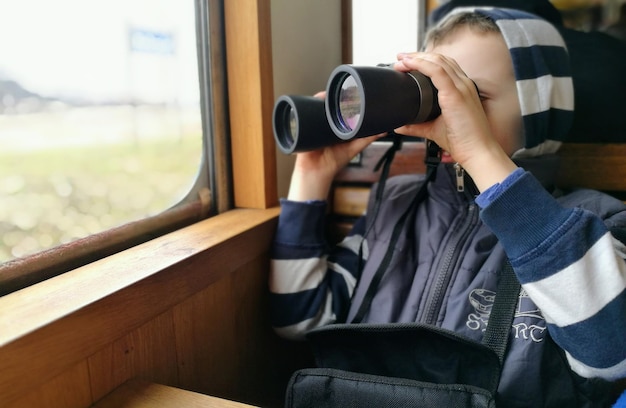 Foto ragazzo che usa il binocolo in treno