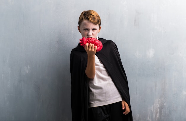 Boy in vampire costume for halloween holidayse eating a heart