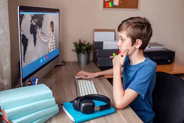 Мальчик видеоконференций с репетитором на компьютере дома дистанционного обучения
