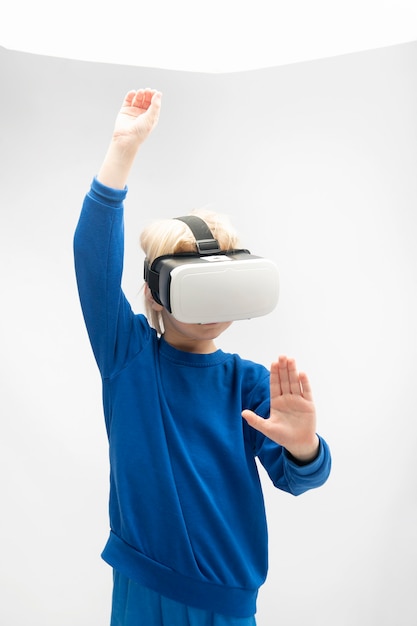 Boy in virtual reality glasses. VR games. White surface. Vertical frame.