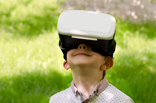 Boy in a virtual reality helmet on a wall of green grass