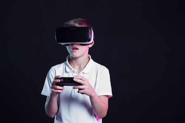 Boy in VR goggles playing with gamepad