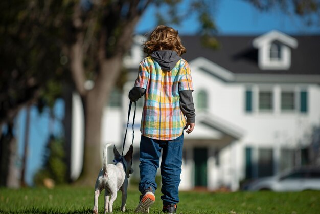 公園で彼女の犬と遊ぶ子犬の面白い子供と一緒に歩く少年
