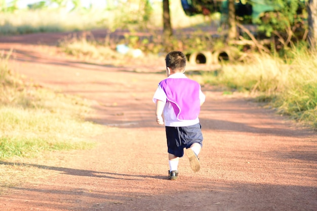 写真 晴れた日に砂道を歩く少年