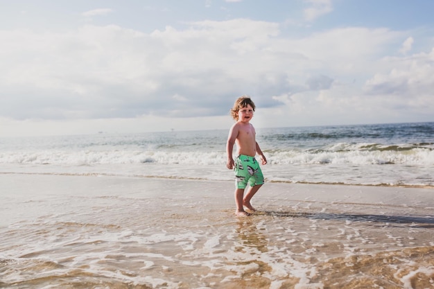 Photo boy walking on sand at beach against sky