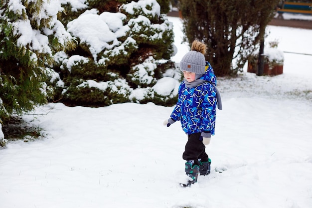 The boy walks in the park in winter when it has snowed a lot\
sculpting snowmen and sledding