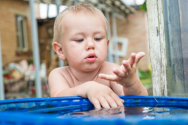 A boy washes his hands in the water barrel