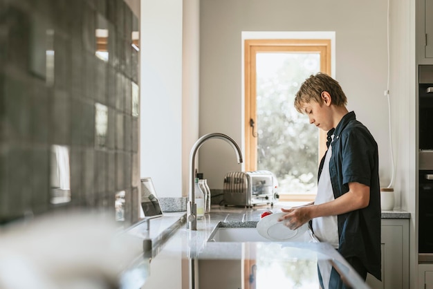 Photo boy washing dishes, household chores for kids