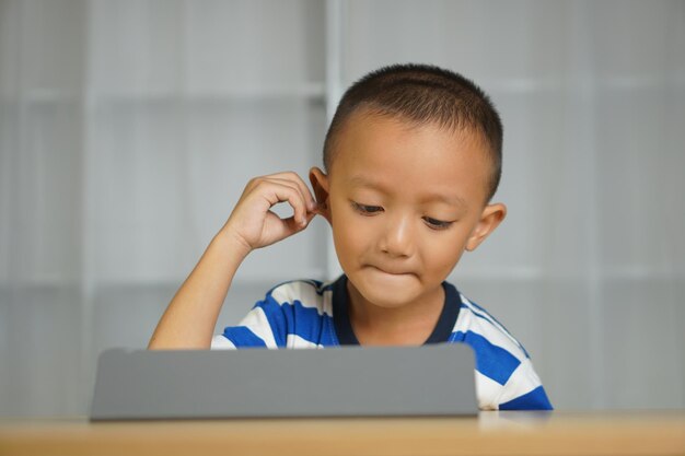 Photo a boy watches a lesson on a portable computer