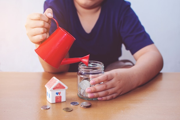 Boy watering House and coins. plan for House concept