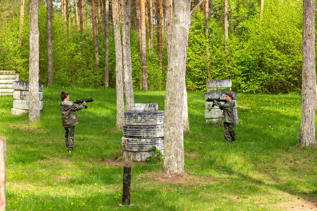 Boy weared in camouflage playing laser tag in special forest playground