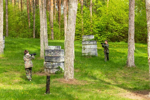 Boy weared in camouflage playing laser tag in special forest playground