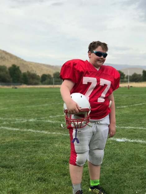 Foto ragazzo che indossa un'uniforme da football americano sul campo da gioco