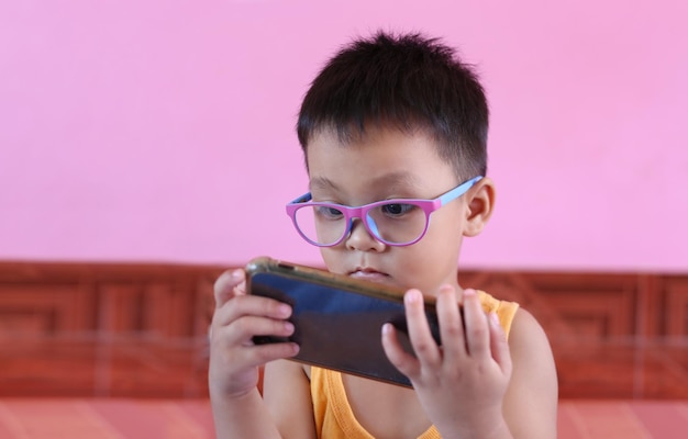 Boy wearing glasses and playing smartphone