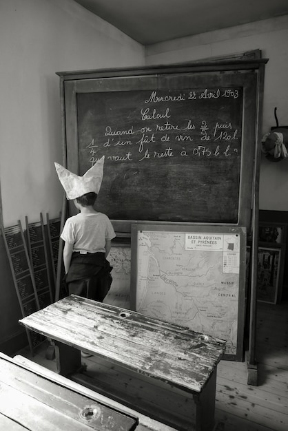 Фото Мальчик в бумажной шляпе, стоя в классе.