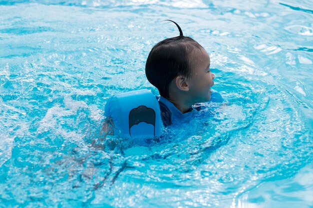 Foto ragazzo che indossa ali d'acqua mentre nuota in piscina