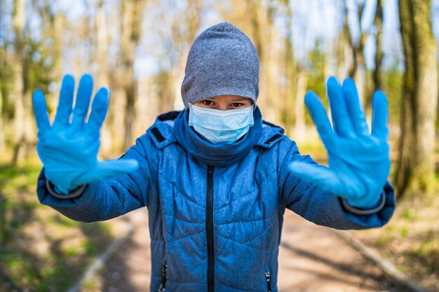 Boy wears medical rubber gloves outdoor Boy holds hands in rubber gloves in front of camera Stop the coronavirus Pandemic COVID19 corona virus epidemic infection quarantine virus colds