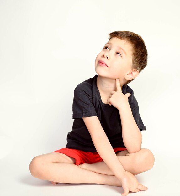 A boy on a white background. Smiling handsome boy sitting on a white background.