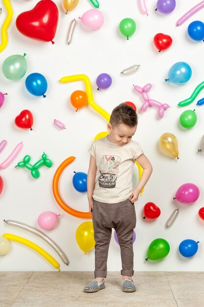 Boy on a white background with colorful balloons boy in a tank top and pants