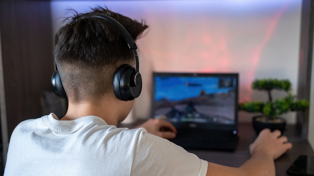 A boy in white t-shirt and headphones playing games on PC