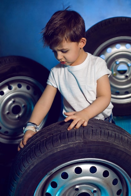 白いTシャツシャツと帽子を着た少年が ⁇ 青色の車輪の背景に座っています ⁇
