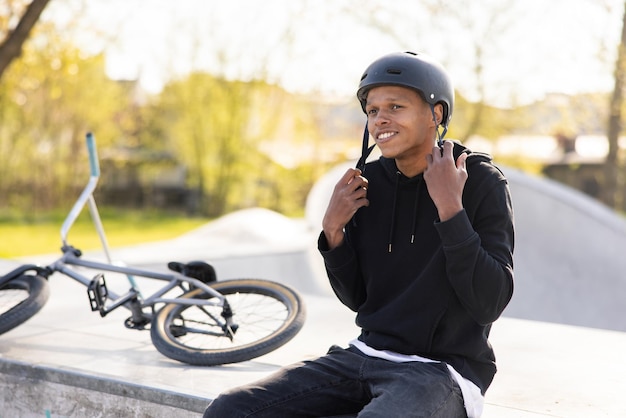 BMXで自転車から落ちて、コンクリートのスロープに座っている男の子が乗る準備をします