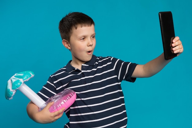 Boy with adorned toy taking selfie on blue background