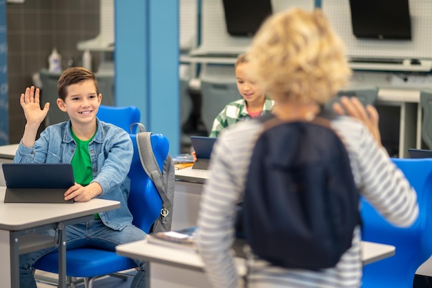 Boy with back to camera greeting classmates