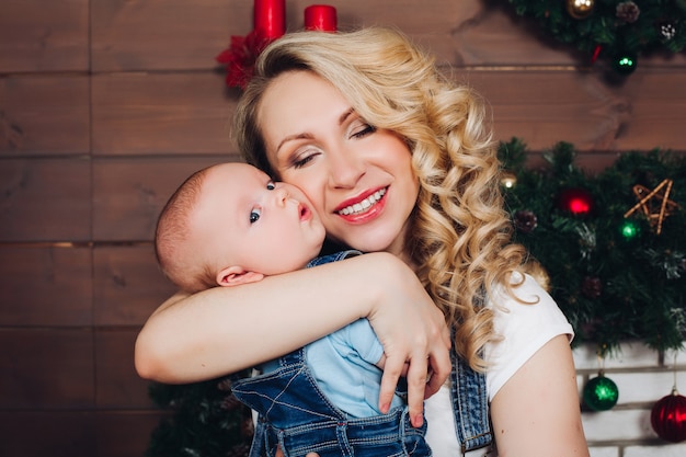 Ragazzo con la bella mamma bionda che abbraccia nella casa decorata per natale