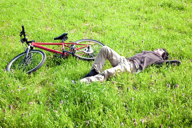 牧草地で横になっている自転車を持つ少年